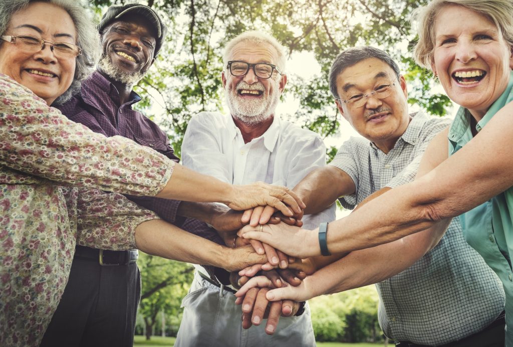 group of elderly individuals putting their hands together